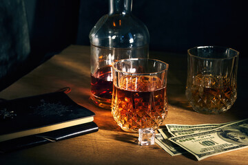 two glasses of iced whiskey and dollars