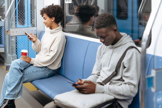 random subway passengers using their smartphones while sitting i