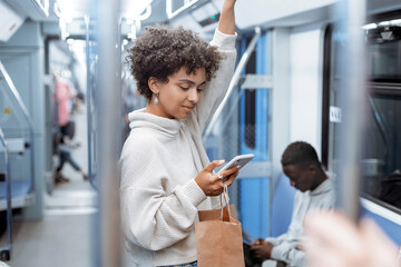attractive woman reading electronic correspondence in a subway car .