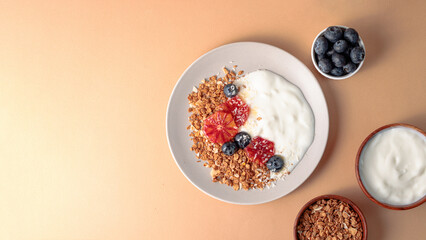 breakfast table with granola bowl with greek yogurt decorated by blood oranges, blueberry and...
