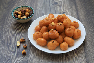 A bowl of Lokma (Turkish), loukoumades (Greeek ) with other names in other languages, are pastries made of leavened and deep fried dough, soaked in syrup or honey, sometimes coated with cinnamon
