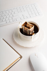 Instant freshly brewed cup of coffee or paper dripping bag on a cup on table with computer keyboard and mouse