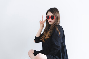 ハートのサングラスをかけてピースサインをする黒いワンピースの女性