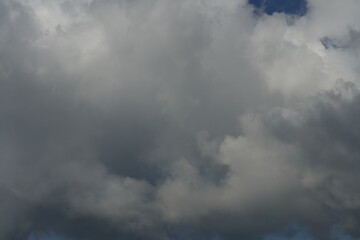 Dichte und kompakte Bewölkung aus unterschiedlich geformten  Wolken am morgendlichen Himmel, blau und weiß