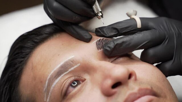 Close up shot of male microblading procedure to making permanent eyebrows makeup