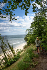 Frau mit Fahrrad an der Steilküste von Usedom (Bansin, Langer Berg) an der Ostsee mit stimmungsvollem Gewitterhimmel