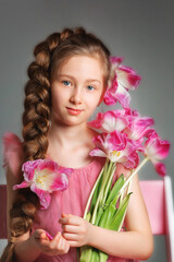 Close portrait of a girl with long hair with an orchid flower on a gray background