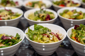 Green vegan salad from green leaves mix and vegetables, side view. set with different salads on table. close-up