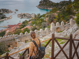 Travel and tourist attractions at Kekova island, Turkey. Woman traveler explores ruins castle of Simena with view of sea bay and Kekova Island with famous flooded city. Tourist attractions in Turkey.