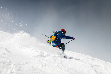 Naklejka na ściany i meble Skiing, skier, frisky - freeride, a man is stylishly skiing on a snowy slope with snow dust plume behind him