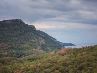 travel to Lagoon in Oludeniz, Fethiye, Turkey. beach near Darbogaz. Winter landscape with mountains, green forest, azure water, beach and cloudy sky