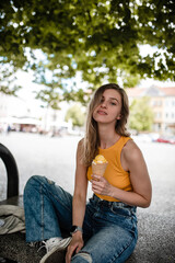 Cute young woman is posing with gelato and enjoying summer time in European town.