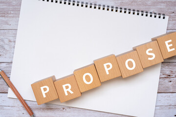 提案・プロポーズのイメージ｜「PROPOSE」と書かれた積み木、ノート、ペン