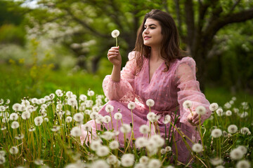 Young woman blowing dandelion seeds