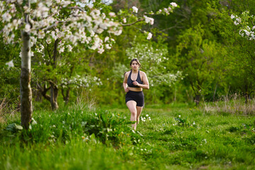 Plus size lady running through an orchard