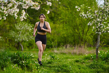 Plus size lady running through an orchard