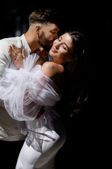 Beautiful caucasian newlywed couple kissing on a background of sunlight with a darkened background
