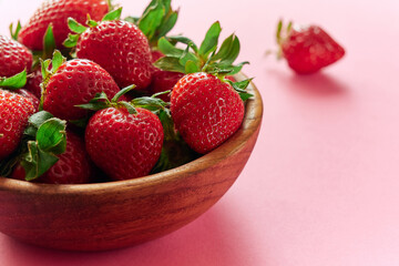 Strawberries in a wooden cup on a pink background