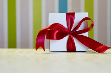 Christmas present, gift, box with red ribbon against colorful background. Abstract texture. New Year morning. Top view. Holiday mood. Valentine's Day. 