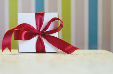 Christmas present, gift, box with red ribbon against colorful background. Abstract texture. New Year morning. Top view. Holiday mood. Valentine's Day. 