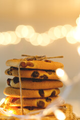 Christmas oatmeal cookies, biscuits on a light background with a beautiful bokeh from a garland. Abstract texture. New Year morning, breakfast. Food.