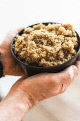 A plate of cooked quinoa porridge in a man's hands. Very healthy carbohydrates. The healthiest cereal in the world. Useful and healthy food.
