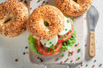 Fresh and healthy golden bagels with tomatoes, lettuce and mozzarella. - obrazy, fototapety, plakaty