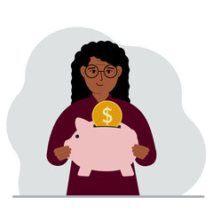 Naklejka premium Happy woman holds a piggy bank, a coin falls into the piggy bank. The concept of saving finance, savings, investing finances.