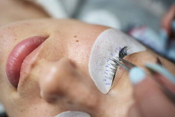 close-up tweezers pull the cilia to the side during eyelash extensions. a special patch is glued under the eye