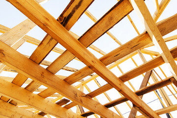 Construction of a wooden frame roof. Fragment of a structure made of large wooden beams. Close-up. Bottom up view