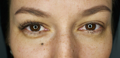 close-up open female eyes. before and after. eyelash extensions on one eye