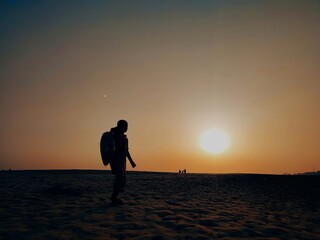 Fototapeta premium The sunset with the boy when walking in the sand desert of Padma. 