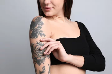Foto op Canvas Beautiful woman with tattoos on arm against grey background, closeup © New Africa