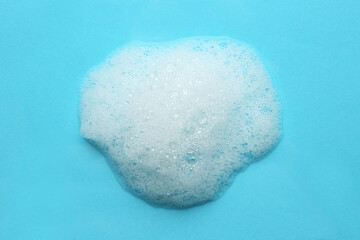 Drop of bath foam on turquoise background, top view