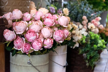 Pink peonies in bucket vases in flower shop. Spring flowers, vintage metal vases with bouquets for sale.