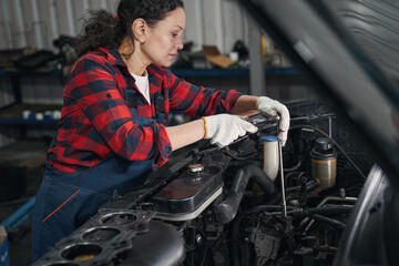 Fototapeta na wymiar Woman auto mechanic repairing car in automobile garage