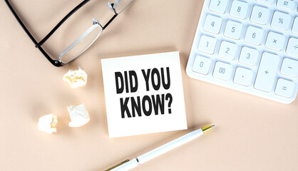 DID YOU KNOW text on sticky with pen ,calculator and glasses on beige background