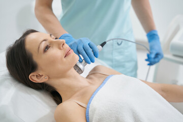 Naklejka premium Beauty expert using RF-therapy on female neck