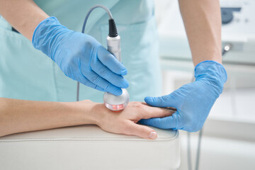 Beauty professional treating vistor hand with radiofrequency therapy