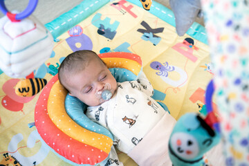 Newborn baby sleeps with passifier on playing mat. Tired and relaxing concept.