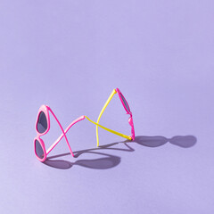 Summer creative colorful  heart shaped sunglasses composition against purple background. Minimal vacation concept. Sun protection idea. Trendy fashion eyewear. Sunlit shadows.
