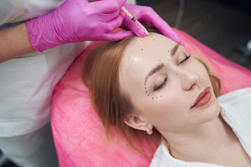Female lying on cosmetology chair and receiving beauty injections