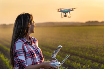 Farmer woman driving drone in agricultural field