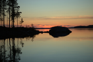 A lovely island in the middle of the northern lake during the sunset. Three swans are heading North in the background.