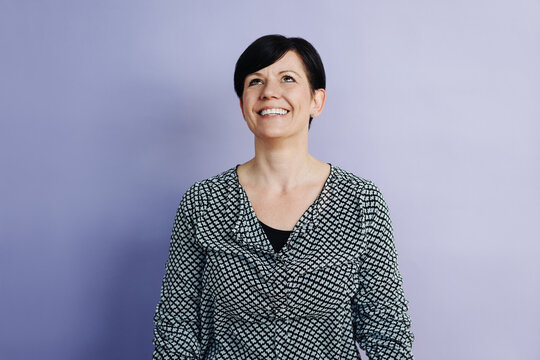 Laughing Woman Looks Up, Against Purple Background With Copy Space