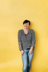 Laughing woman against a yellow background with copy space