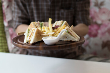 hand holding sandwich tray cream with sauce , blurry background.