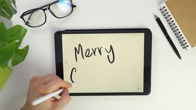 Merry Christmas note Write text on tablet screen. Electronic pencil for widget notes. Modern reminder on screen. Top view of white desktop office. Screen glasses. Pocket laptop for modern reminders.