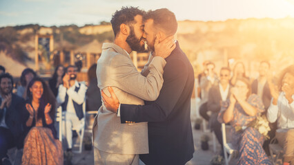 Handsome Gay Couple Exchange Rings and Kiss at Outdoors Wedding Ceremony Venue Near the Sea. Two Happy Men in Love Share Their Big Day with Diverse Multiethnic Friends. LGBTQ Relationship Goals.