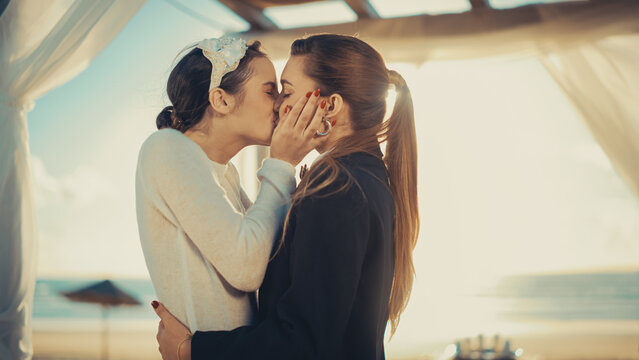 Close Up of Female Queer Couple Exchange Rings and Kiss at Outdoors Wedding Ceremony Near Sea. Happy Two Lesbian Women in Love Say Their Vows and Get Married. LGBTQ Relationship Goals.